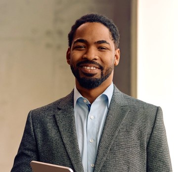 Smiling man in a light blue button-down and gray sport coat.